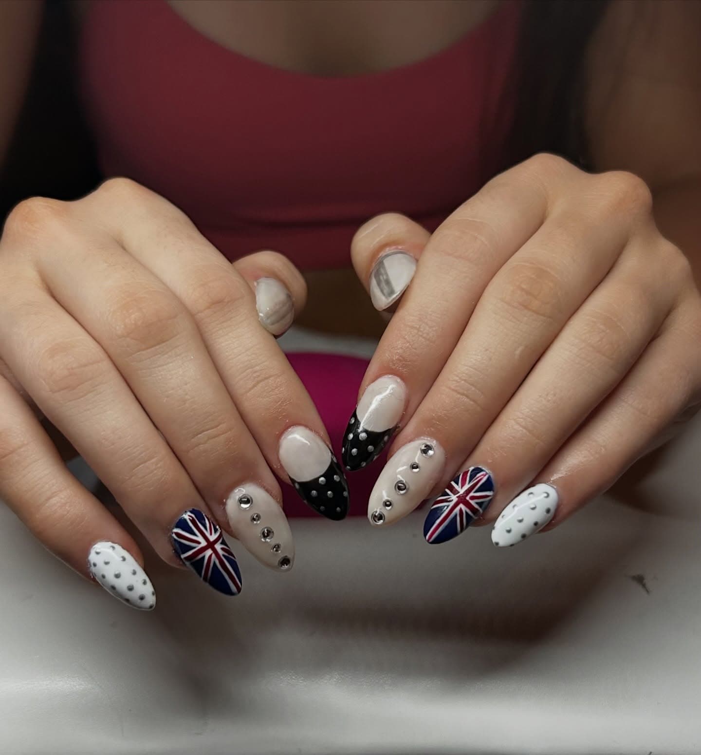 Almond nails in milky white mixing Union Jack flags, crystal lines, silver stud dots and black polka-dot French tips