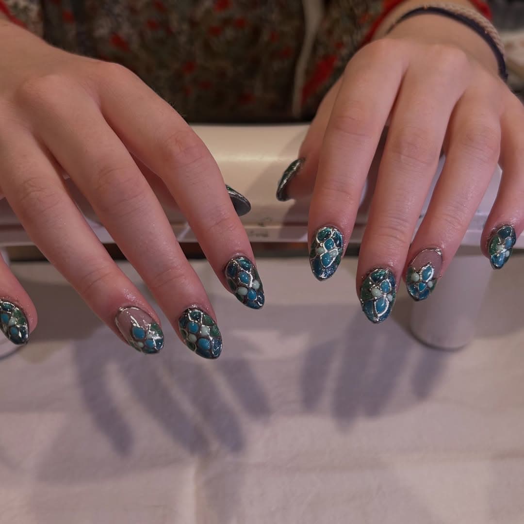 Almond nails covered in a teal and seafoam mermaid mosaic outlined in liquid silver like stained glass